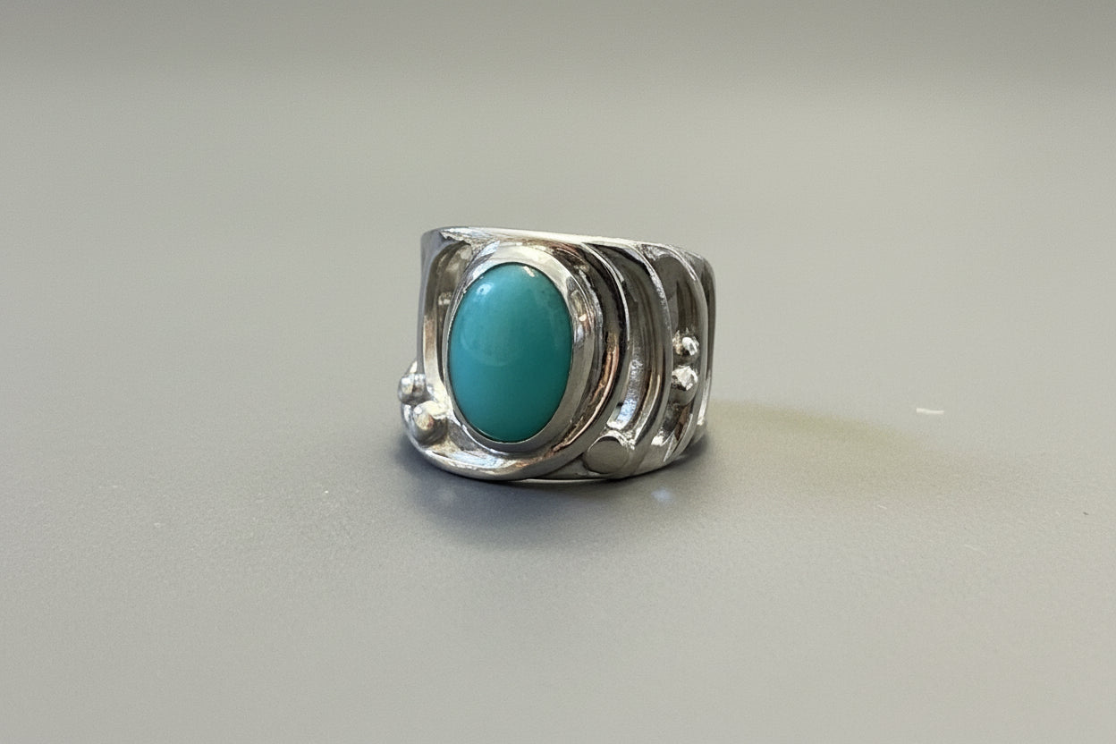 Silver ring with a turquoise coloured stone on a gray surface