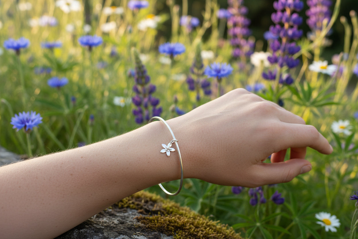 Silver bangle with a star flower charm on a white backgroun