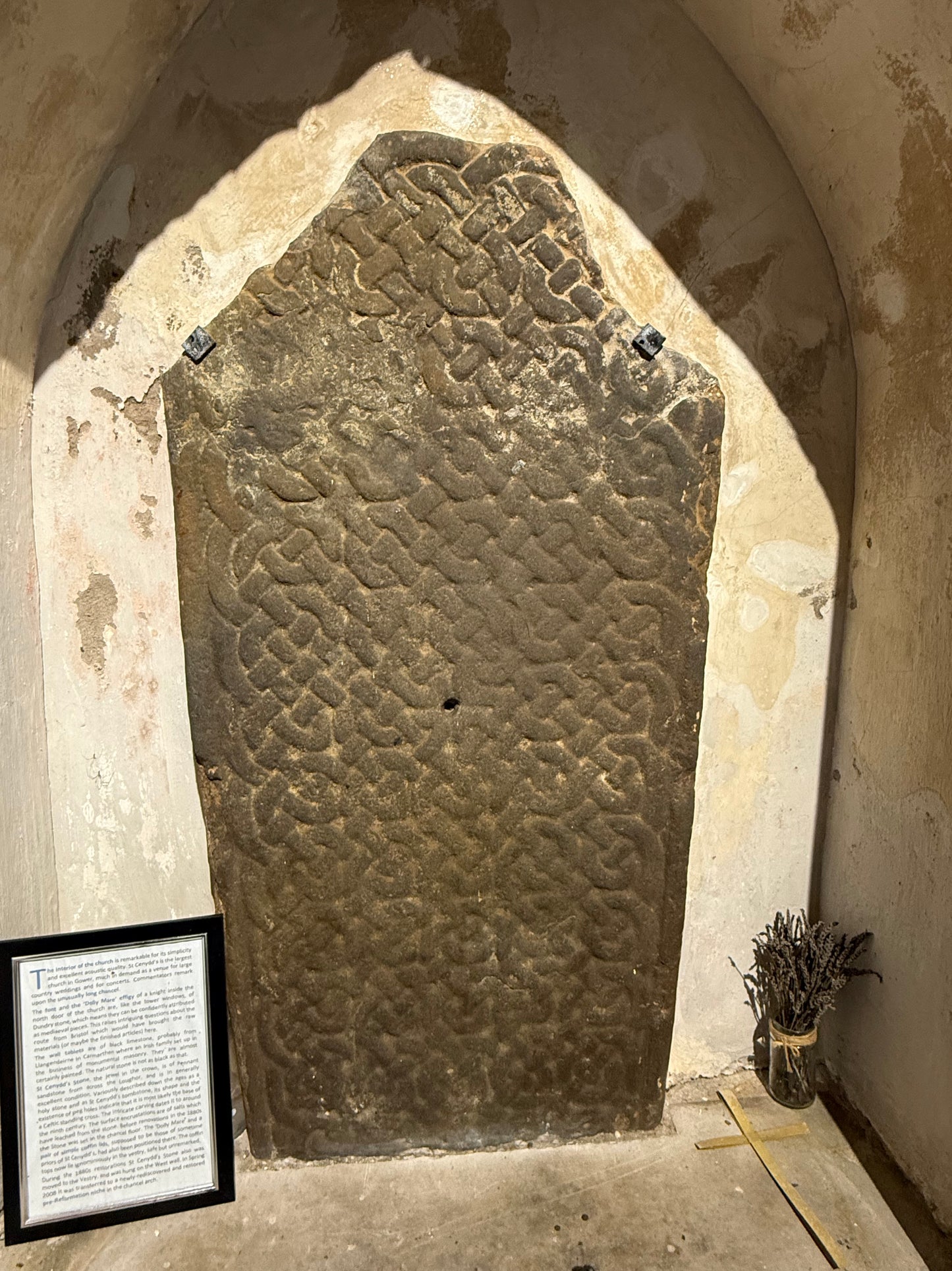 Decorative Celtic stone pillar with intricate knotwork patterns in a Welsh church