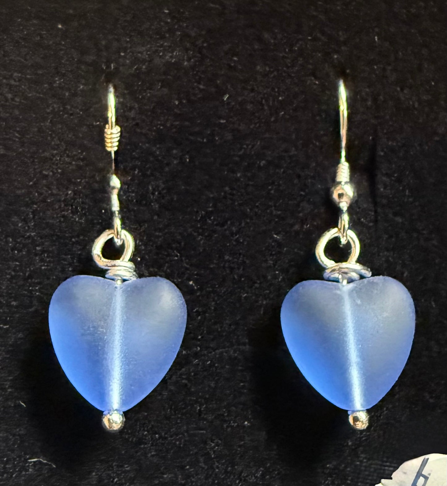 Blue heart-shaped earrings on a black background