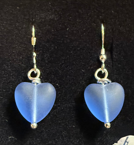 Blue heart-shaped earrings on a black background