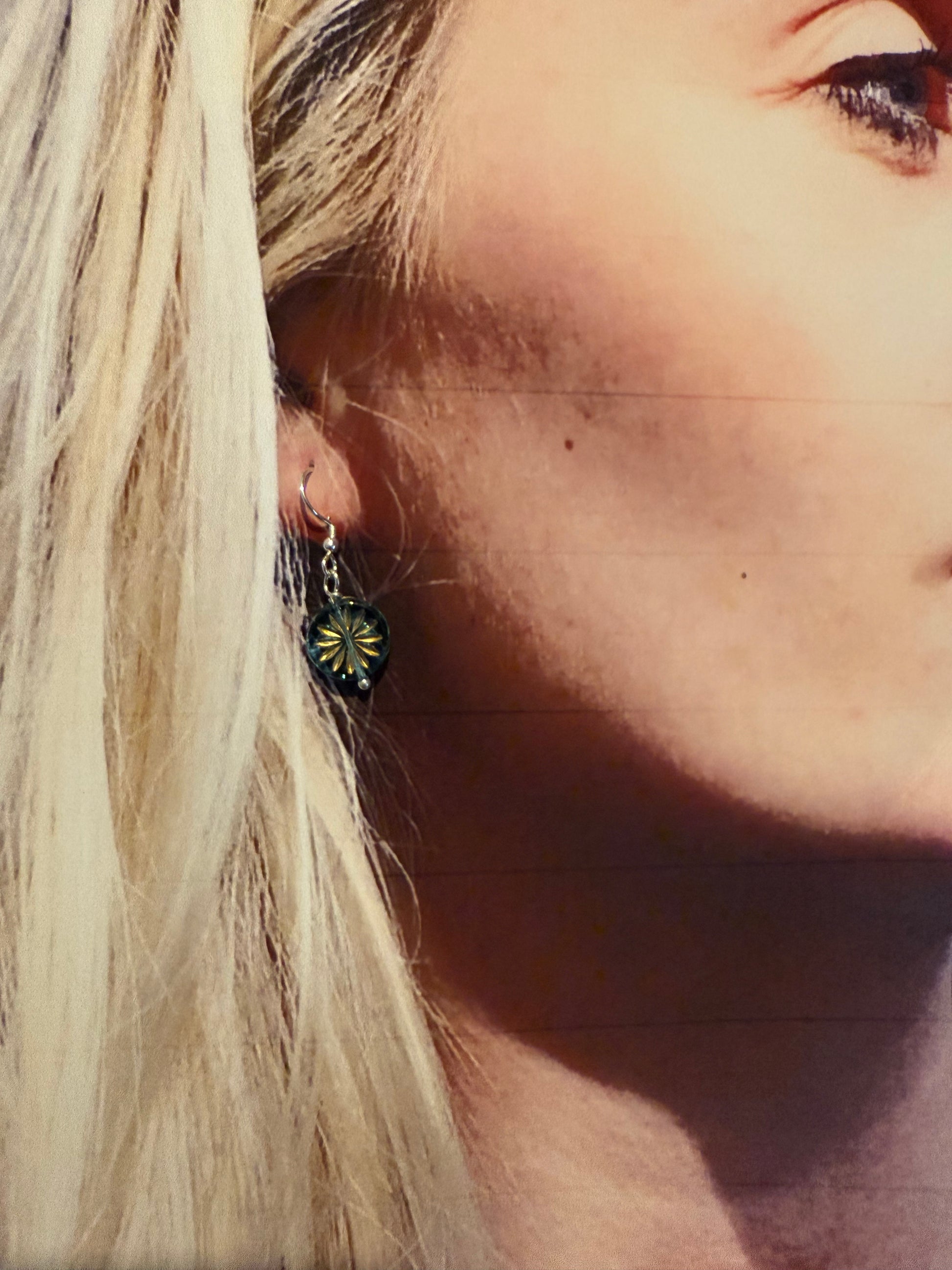 Turquoise glass daisy earrings on a model 