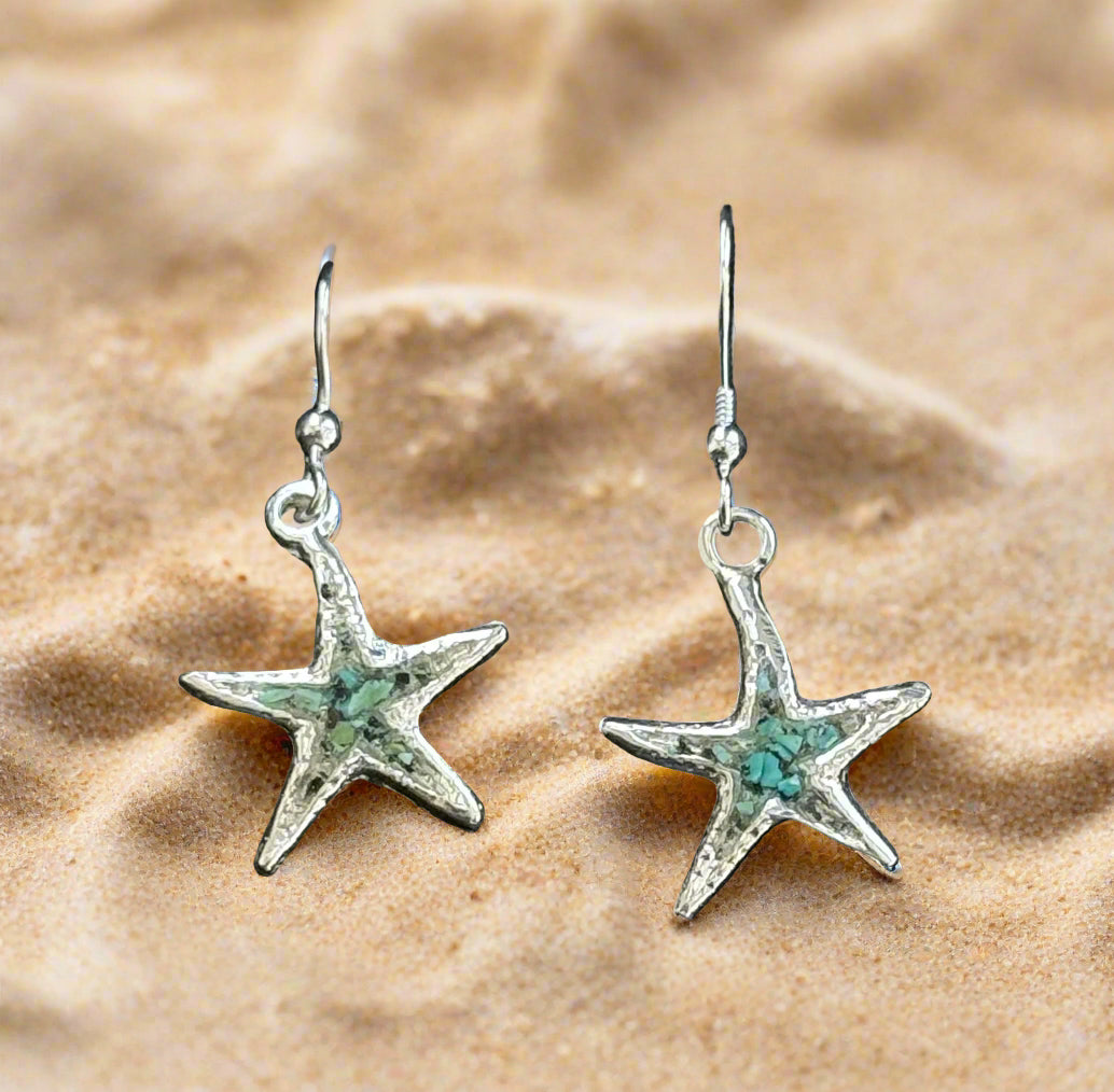 Star-shaped earrings with turquoise stones on a black background