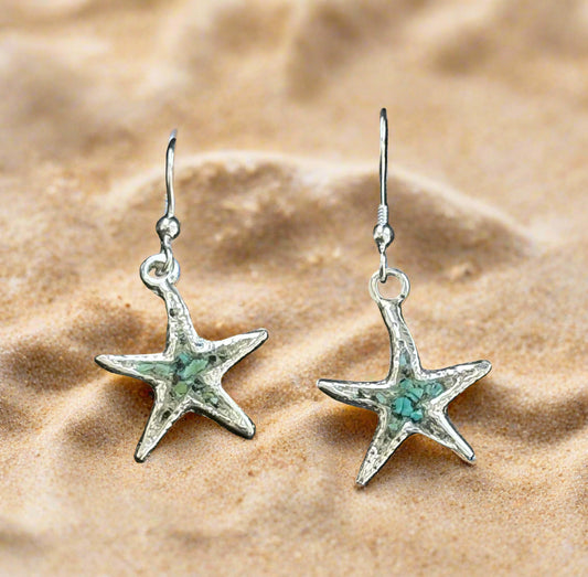 Star-shaped earrings with turquoise stones on a black background