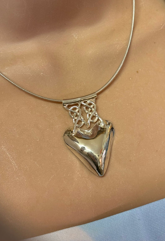 Silver celtic necklace with a heart-shaped pendant on a person's neck
