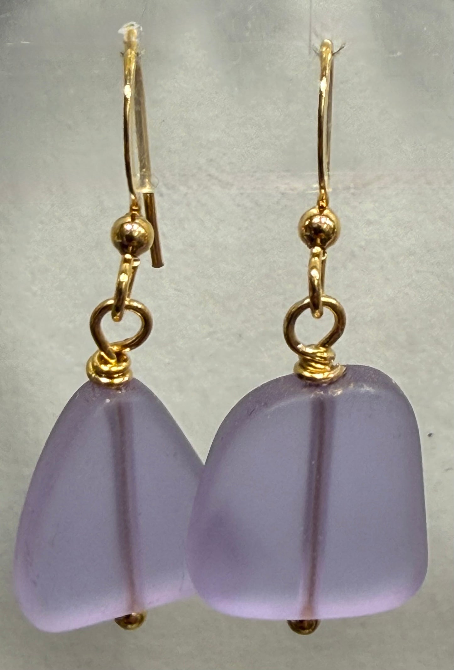 Purple earrings with gold hooks on a light gray background