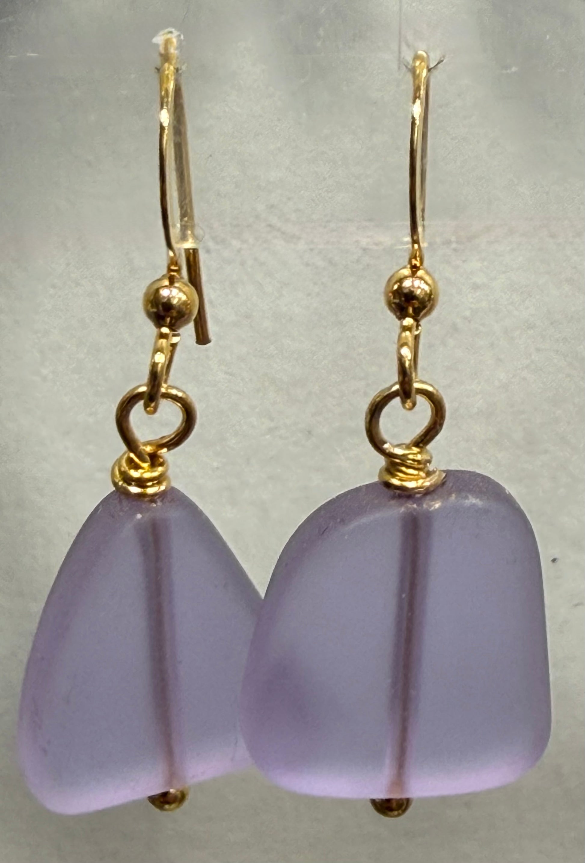 Purple earrings with gold hooks on a light gray background