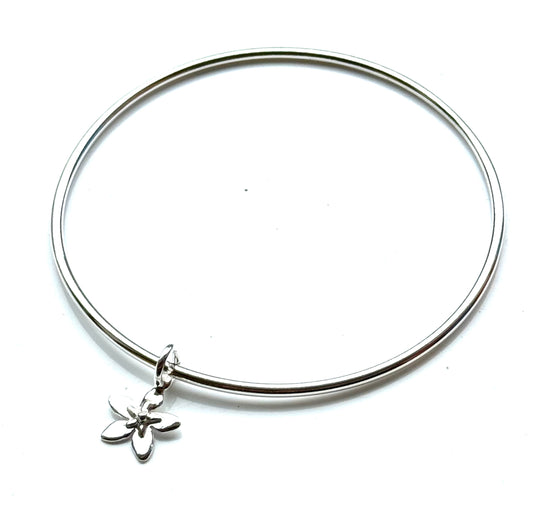 Silver bangle with a star flower charm on a white background